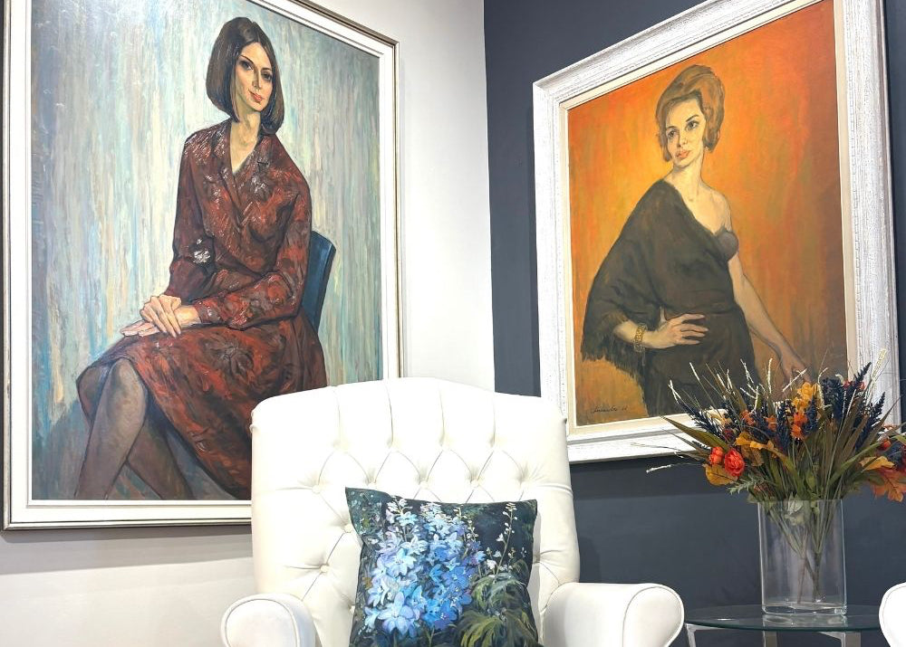 White armchair with a blue pillow in a room with framed portraits on the wall.